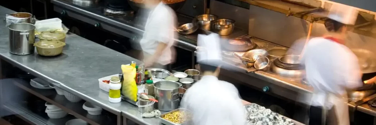Cozinha de restaurante com chefs em movimento, simbolizando o trabalho em equipe e a eficiência operacional em restaurantes de São Paulo.
